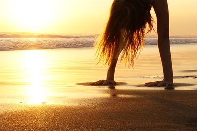 Woman standing at beach during sunset