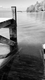 Wooden posts in sea against sky