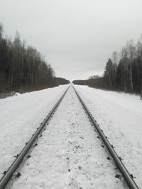 Snow covered railroad tracks against sky during winter