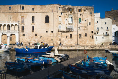 Boats moored in canal by buildings in city