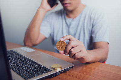 Midsection of man using mobile phone while sitting on table