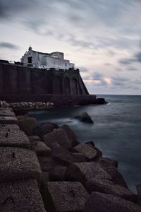 Rocks by sea against sky during sunset