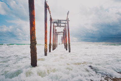 Wooden posts on beach against sky