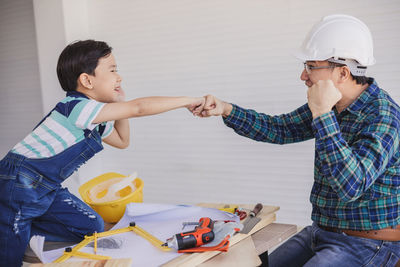 Father giving fist bump to son while working