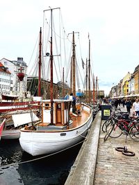 Sailboats moored at harbor against sky