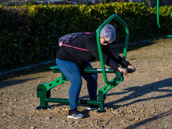 Full length of senior woman exercising at playground