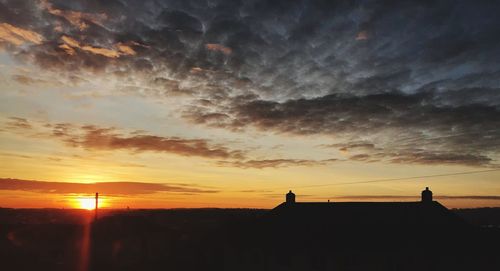 Silhouette city against sky during sunset