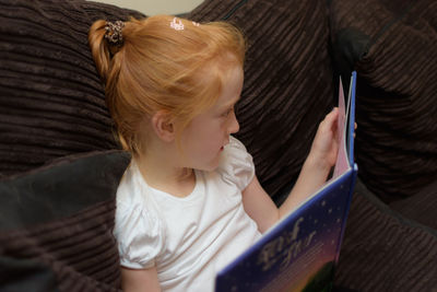 Rear view of girl using mobile phone at home