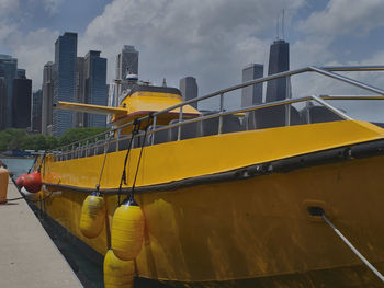 Yellow moored by building against sky