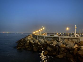 Illuminated rocks by sea against sky at night