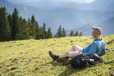 Man sitting on field against mountain range