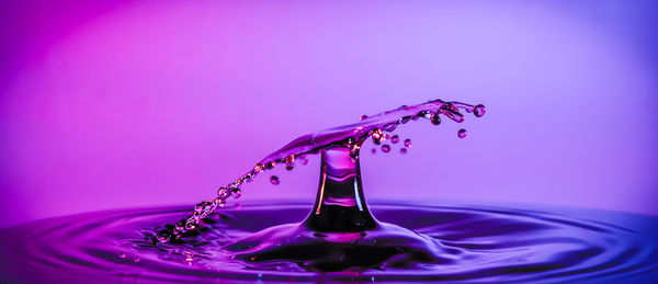 Close-up of water splashing against purple background