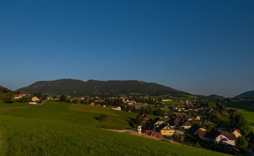 Scenic view of landscape and houses against clear blue sky