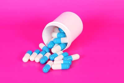 High angle view of capsules in container over pink background