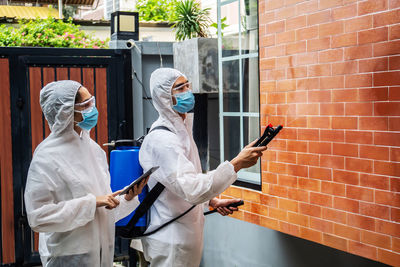 Man and wearing protective suit disinfecting house