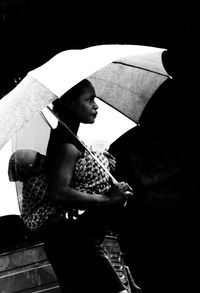 Side view of woman with umbrella standing in rain