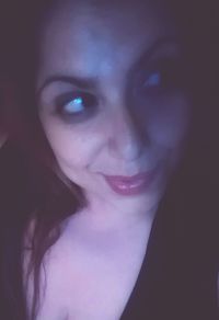 Close-up portrait of a smiling young woman over black background