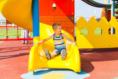 Full length of boy sitting on yellow playground