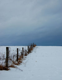Wooden posts on frozen sea against sky