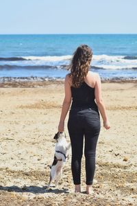 Rear view of woman with dog on beach