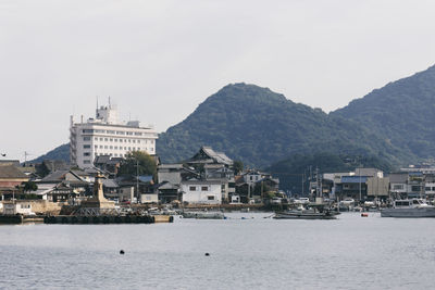 Sea by buildings in city against sky