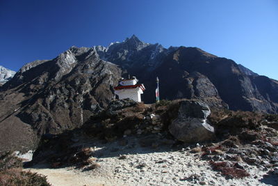 Rocks on mountain against clear blue sky with buddhism monastery