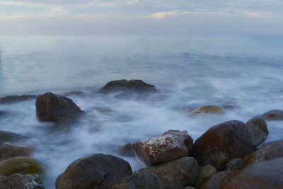 Scenic view of rocks in sea against sky