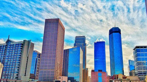 Low angle view of modern buildings against cloudy sky