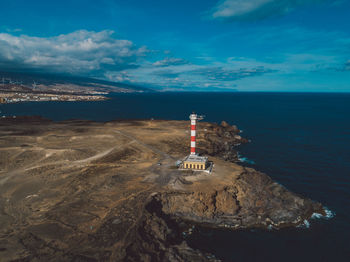 Lighthouse by sea against sky