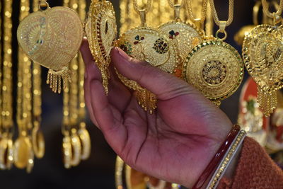 Cropped hand of woman holding necklace pendants in store