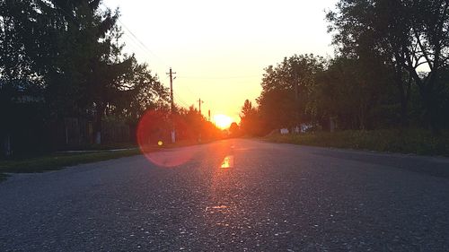 Road amidst trees against clear sky during sunset