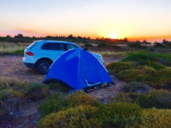 Tent on land against sky during sunset