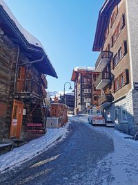 Road amidst buildings against sky during winter