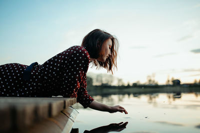 Woman with umbrella in lake against sky