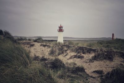 Lighthouse by sea against sky