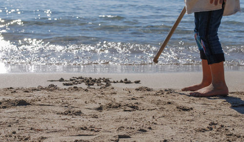 Low section of man standing on beach