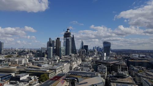 Aerial view of buildings in city against cloudy sky