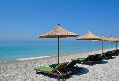 Deck chairs on beach against clear sky