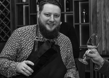 Portrait of smiling man holding bottle in restaurant