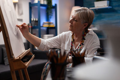 Side view of young woman using mobile phone while sitting at restaurant