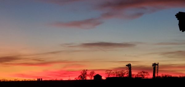 Silhouette trees on field against sky during sunset