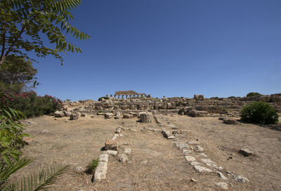 Built structure on landscape against clear blue sky