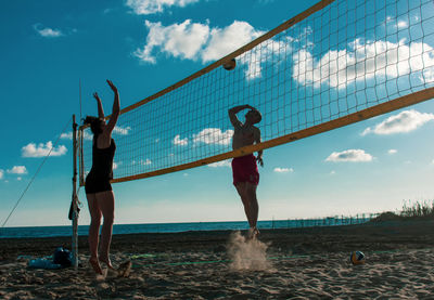 People playing beach volleyball against sky