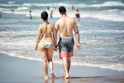 Rear view of people walking on shore at beach