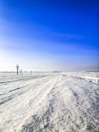 Scenic view of snow covered field against blue sky