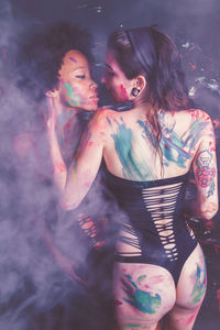 Young women wearing bikini while covered in body paint at nightclub