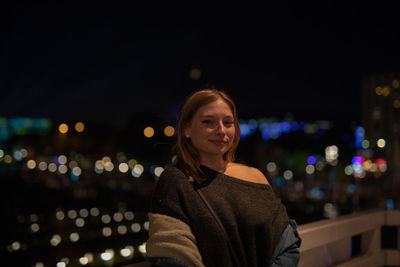 Portrait of young woman standing in city at night