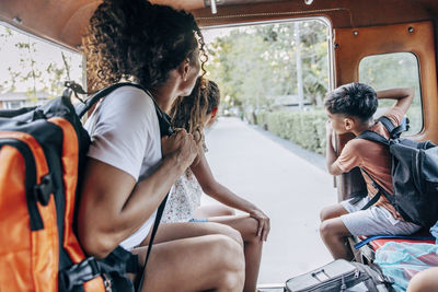 Side view of mother holding backpack while sitting in tuk-tuk with son and daughter on vacation