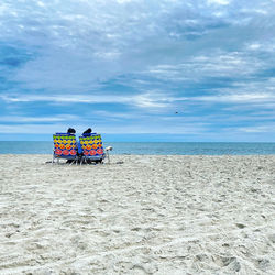 Rear view of people on beach against sky