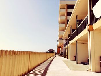 Empty footpath amidst buildings against clear sky